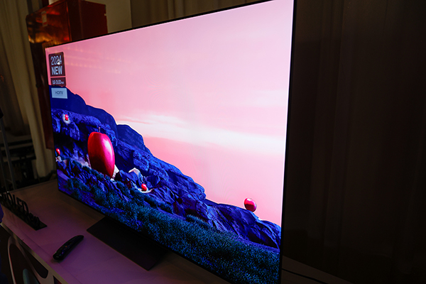 טלוויזיה המציגה סצנת טבע עם תפוחים אדומים על פני שטח סלעי ושמים ורודים ברקע.
