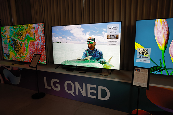 תצוגה של טלוויזיות LG QNED, עם תמונות מוצגות ושלטי מידע, עומדת בשורה בתוך אולם תצוגה.