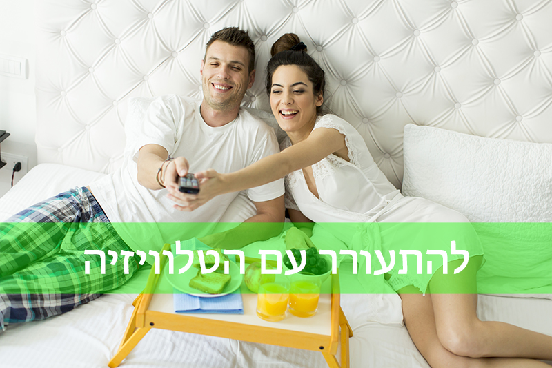 גבר ואישה יושבים על מיטה, מחייכים ומחזיקים שלט. מולם מגש ארוחת בוקר עם מיץ ופירות. התמונה כוללת טקסט בעברית.